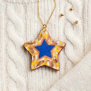 Vue détaillée d'un pendentif étoile en céramique peint à la main sur un fond de tricot.