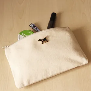 Detail view of a Labrador guide dog enamel pin attached to a canvas makeup pouch.