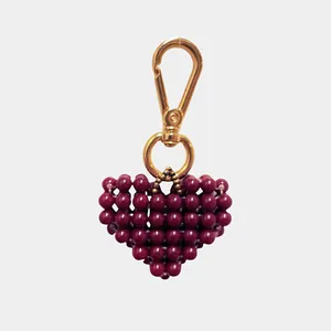 Dettaglio di un ciondolo a cuore in perline rosso scuro con chiusura a moschettone dorata.