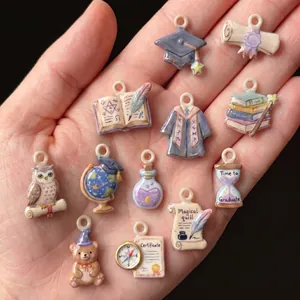 Close-up of assorted graduation and magic themed ceramic charms held in a hand