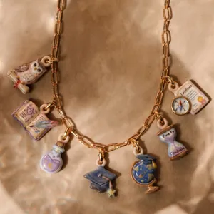 Detailed macro shot of a gold graduation necklace with owl, cap, and certificate charms