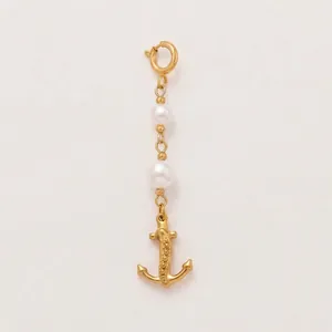 Détail d'un pendentif ancre en acier doré 18 carats avec deux élégantes perles blanches
