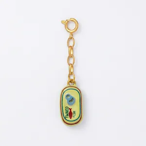 Detailed macro view of a quirky enamel tinned fish can charm on a gold-tone link chain