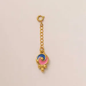 Detailaufnahme eines goldenen Lutscher-Anhängers mit blauem und rosa Emaille-Wirbel.