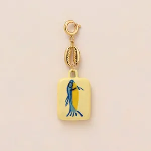 Gros plan d'un pendentif en acier inoxydable doré avec coquillage et motif poisson d'été.