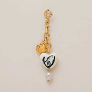 Dettaglio charm bikini con perla, conchiglia dorata e cuore floreale per costumi
