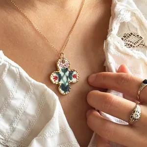 Vintage cross pendant necklace with hand-painted floral pattern and gold scalloped edge.