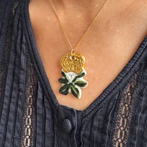 Close-up detail of unique gold and green portrait pendant on black lace shirt