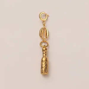 Detailed macro view of a gold-toned bottle and cowrie shell charm pendant for jewelry