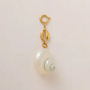 Detailed shot of a gold ocean shell pendant with a natural pearl snail shell charm.
