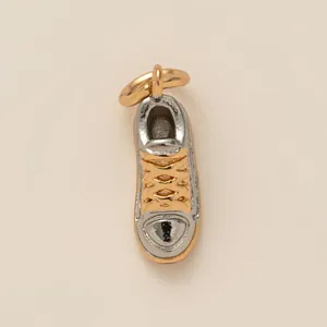 Primo piano dettagliato di un ciondolo a forma di scarpa sportiva bicolore in oro e argento