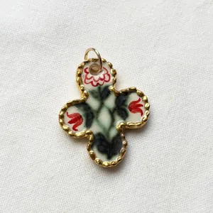 Close-up of a vintage floral pattern quatrefoil pendant with elegant gold scalloped edges.