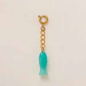 Detail view of a translucent turquoise fish pendant with a gold stainless steel chain