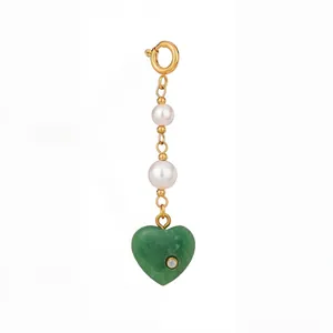 Detailed macro view of heart pendant featuring green gemstone accents and elegant white pearls