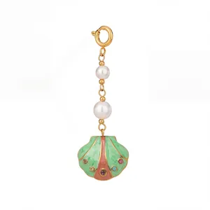 Detailed view of a seashell pendant featuring white pearls and green enamel finish