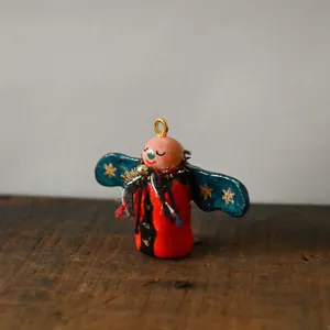 Detailed view of a unique handcrafted abstract doll pendant featuring gold stars.