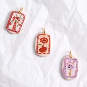 Vista detallada de colgantes florales de cerámica con ilustraciones de tulipanes y rosas.