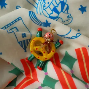 Close-up detail of a whimsical pretzel-shaped doll pendant on soft patterned fabric