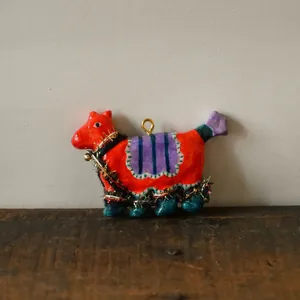 Detailed view of hand-painted abstract horse pendant with tinsel decor on rustic wood