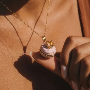 Nahaufnahme einer rosa Macaron-Anhänger-Halskette mit Kronendetail und goldener Vintage-Kette