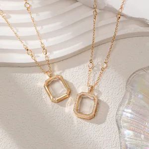Close-up of gold minimalist locket necklace with transparent rectangular glass box pendant.