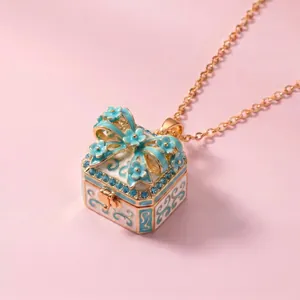 Close-up of an ornate blue floral enamel gift box pendant necklace with a golden chain