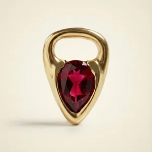Detailed view of a pear-shaped red gemstone set in an 18K gold horseshoe pendant
