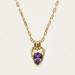 Close-up of 18K gold-plated necklace with teardrop purple zircon in horseshoe pendant
