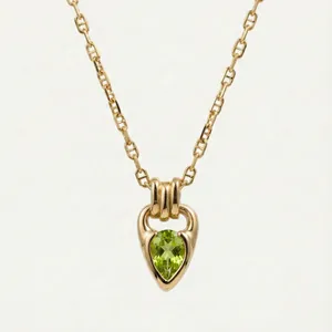 Detail view of a gold-plated horseshoe buckle necklace with a green pear-cut gemstone.