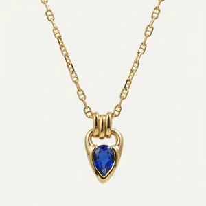 Detail of a teardrop-shaped blue zircon pendant on an 18K gold-plated necklace chain