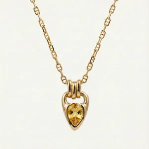 Detailed macro view of gold plated necklace with teardrop yellow zircon and horseshoe bail