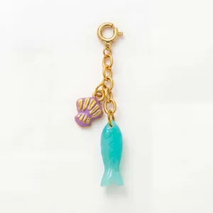Detail view of golden charm with purple shell and turquoise fish pendants