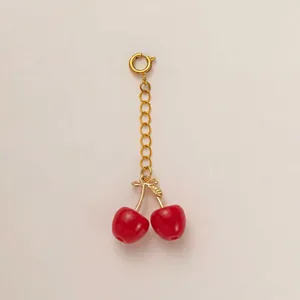 Close-up of red cherry pendant charm with golden metal chain for swimsuit decoration