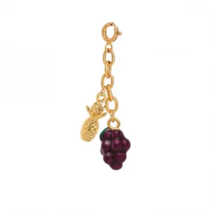 Close-up of gold chain accessory featuring pineapple and purple grape fruit charms