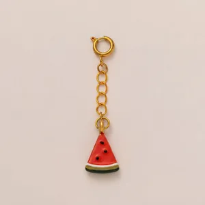 Close-up of a colorful enamel watermelon slice charm with a gold-tone clasp.