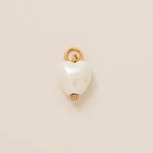Detailed view of a white pearl-finish heart pendant featuring a gold-tone loop connector.