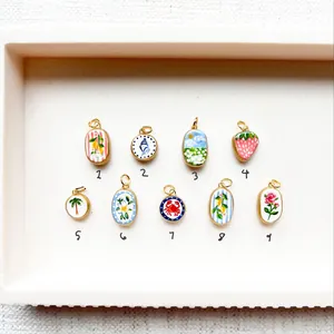 Ensemble de breloques en émail peint à la main avec divers motifs sur plateau blanc