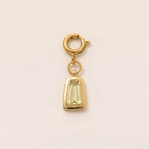 Detail of a gold pendant with a trapezoidal pale yellow gemstone and a circular clasp.