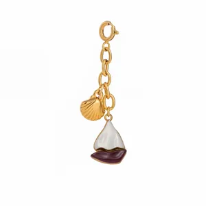 Macro view of a gold-tone nautical charm featuring a sailboat and sea shell design.
