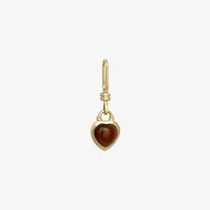 Detail of a vintage 18K gold plated heart pendant set with a polished dark red gemstone
