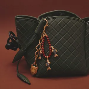 Dettaglio del ciondolo per borsa in stile cinese con carpa koi, pantera e perline rosse.