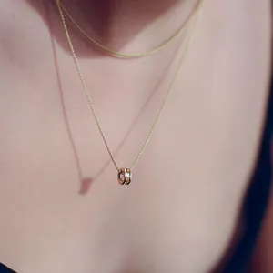 Close-up detail of a minimalist rose gold necklace with a hollow zircon bead pendant