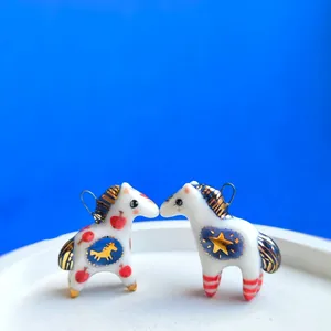 Vista dettagliata di due simpatici ciondoli a forma di cavallo in ceramica con motivi blu e oro