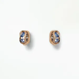 Detail shot of rose gold charms featuring baguette and round blue zircon gemstones.