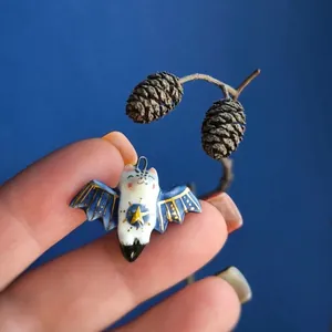 Dettaglio ravvicinato di un ciondolo a pipistrello in ceramica con ali blu e una stella