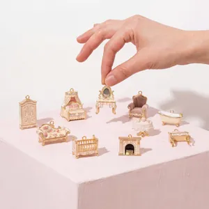 Sammlung von rosa Miniatur-Möbelanhängern, die zur Größenorientierung gehalten werden