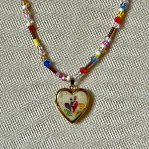 Macro view of vintage heart locket necklace with colorful beads and floral pattern