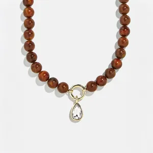 Macro view of teardrop zircon pendant on brown beaded stainless steel necklace