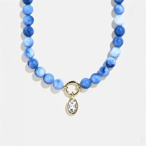 Detailed macro view of blue marbled beads and clear zirconia pendant on gold necklace
