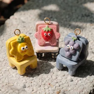 Close-up of three cute cartoon fruit pendants displayed on colorful miniature chair stands